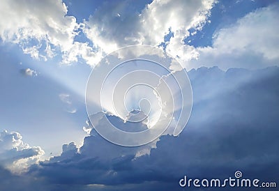 The sun rays behind the cumulus clouds Stock Photo