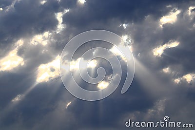 The sun's rays pass through cracks, holes in gray storm clouds. Rainy, cloudy weather. The sun appears behind the clouds Stock Photo