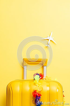 Introduce your island trip with top-view vertical image featuring yellow suitcase, tiny airplane model on yellow background Stock Photo