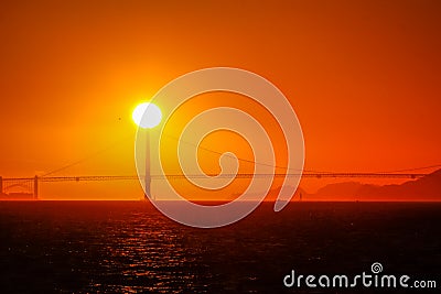 The sun setting behind the Golden Gate Bridge in the San Francisco Bay. Stock Photo