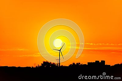 The sun is setting next to a windmill Stock Photo