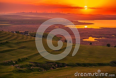 Sun setting over a field of eolian wind turbines and a valley wi Stock Photo