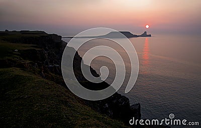 Sun Setting over Worms Head, Rhossili The Gower, South Wales Stock Photo