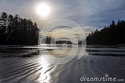 Sun sinks to horizon over rippled sand at Schooner Cove Stock Photo