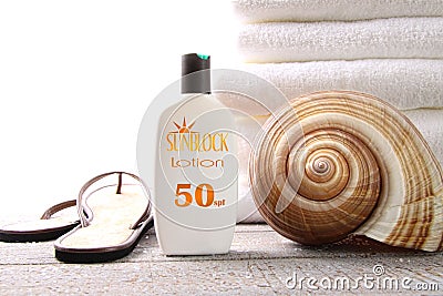 Sunblock lotion, sandals and white towels Stock Photo