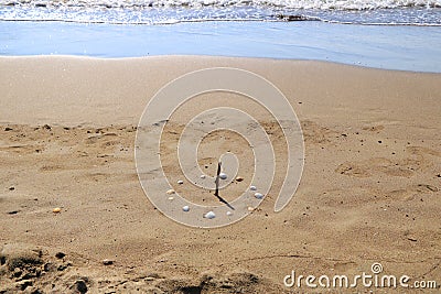 Sundial Made with Seashells on Beach Against Sea Stock Photo