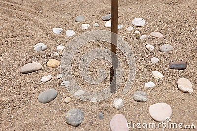 Sundial made of stones on sand closeup background Stock Photo