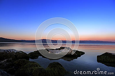 Sundown over the lake and big mossy stones in the water Stock Photo