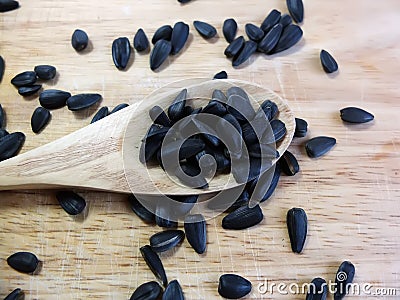 Sunflower Black Seeds in Wooden Spoon and Table Close Up Stock Photo