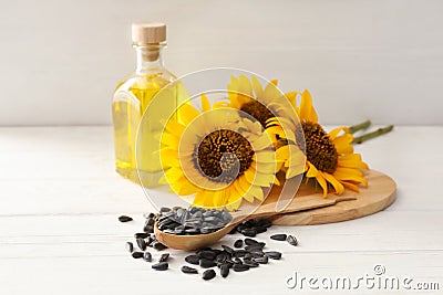 Sunflowers, bottle of oil and seeds on white wooden table Stock Photo