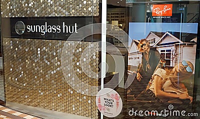Sunglass Hut retail store exterior with huge Ray-Ban advertisement poster on display. Editorial Stock Photo