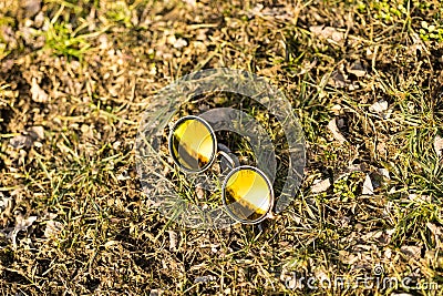 Sunglasses with golden round lenses shoot outside in the nature in a summer day closeup. Selective Focus Stock Photo