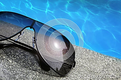 Sunglasses next to a pool Stock Photo