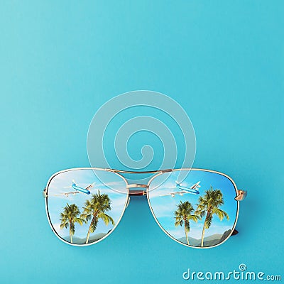 Sunglasses with palm trees, a plane and mountains reflected in them. Concept on the theme of vacation and travel with copy space Stock Photo