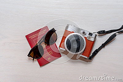 Sunglasses with the passport of a citizen of the Russian Federation and an instant photo camera on a white wooden background Stock Photo