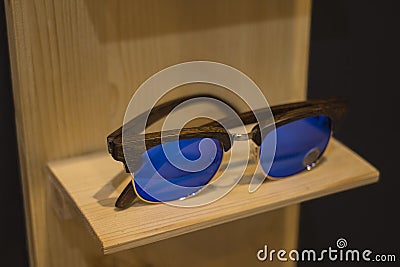 Sunglasses shop with wooden frames in stylish trendy new design on natural wood rack. Stock Photo