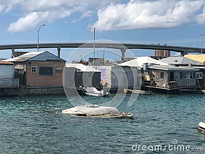 Sunken boats in water behind poor run down houses Stock Photo