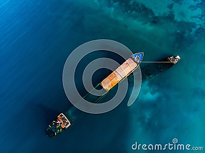 Sunken cargo ship near coast of sea city, large abandoned rusty vessel in water, aerial view Stock Photo