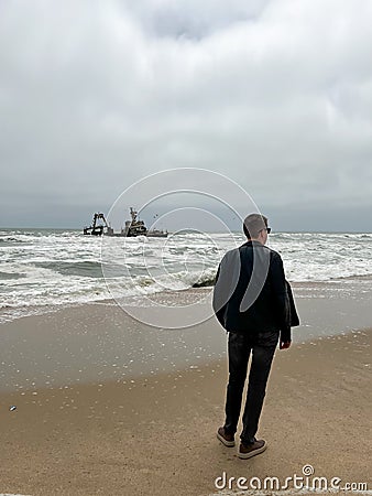 Sunken trawler, shipwreck. Ship Zeila at Skeleton Coast Namibia. Man stands. Stock Photo