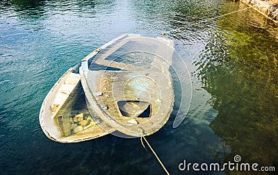 Sunken wooden boat in sea or lake tied to shore. Stock Photo