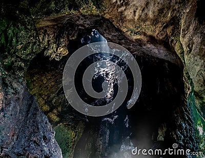 Sunlight coming through the opening roof of cave. Sun shining down in darkness Stock Photo