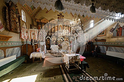 Sunlight lightens the iconostasis in the temple. A lonely grandmother sits on a bench and prays. Transcarpathia, Ukraine Stock Photo