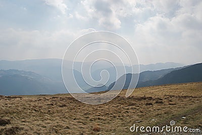 Sunlight; rays and sunbeams through hazy clouds above misty mountains Stock Photo