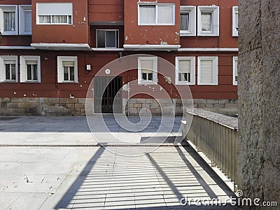 Pontevedra, Spain; 08/09/2018: Sunlight shines through metal fence and makes geometric stripes shadows on the stone ground Editorial Stock Photo