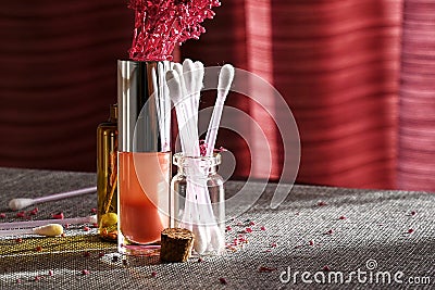 Sunlit cosmetic jars with lip gloss, cotton buds and decorative lilac branch Stock Photo