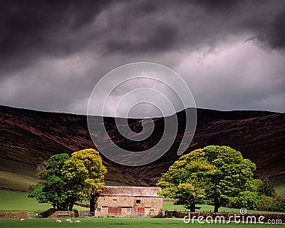 Sunlit trees and barn with gloomy sky background in Edale, Derbyshire in the Peak District, UK Stock Photo