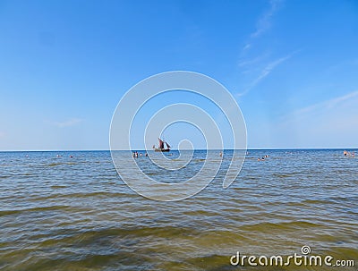 Sunny beach and blue water and a pleasure boat on the shore of the Gulf of Riga. 29, July, 2018, Latvia, Jurmala Editorial Stock Photo