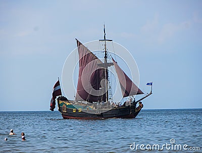 Sunny beach and blue water and a pleasure boat on the shore of the Gulf of Riga. 29, July, 2018, Latvia, Jurmala Editorial Stock Photo