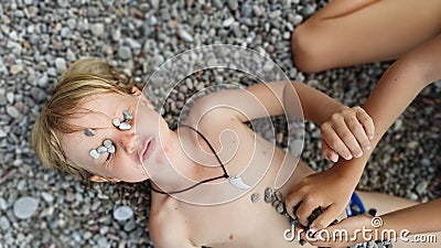 On sunny beach kids lying on pebble, warming after swimming Stock Photo