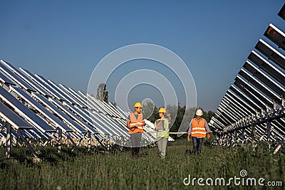 In a sunny day at photovoltaic solar farm walking in front of the camera group of investors and ecological engineer they Stock Photo