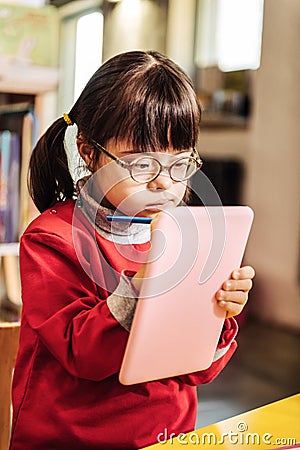 Beautiful little sunny girl feeling joyful while drawing pictures Stock Photo