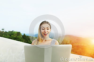 Sunny light portrait of young girl using laptop, mountains in background, Thailand. Stock Photo