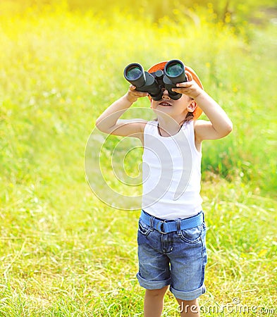 Sunny photo child boy looks in binoculars outdoors in summer Stock Photo