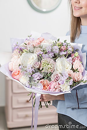 Sunny spring morning. Young happy woman holding a beautiful luxury bouquet of mixed flowers. the work of the florist at Stock Photo