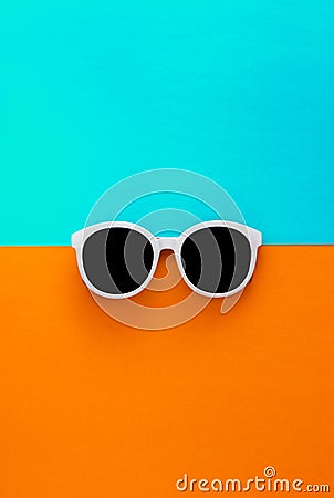 Sunny stylish white sunglasses on a bright blue-cyan and yellow-orange background, top view, isolated. Copy space. Flat lay Stock Photo