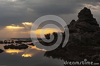 Sunrays break through the clouds over tufa silhouettes at Mono Lake during sunrise Stock Photo