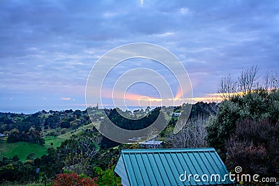 Sunrays break through stormy clouds behind golden vineyards in the valley, colourful trees on the slopes, and distant Stock Photo