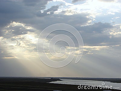 Sunrays through Clouds spreading over a River Stock Photo