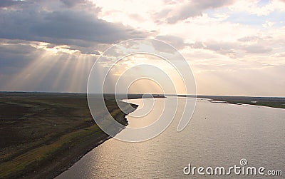 Sunrays through Clouds spreading over a River Stock Photo