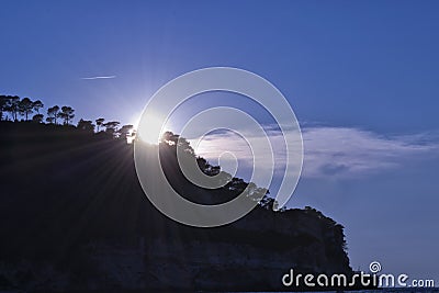 Peschici, Gargano, Apulia, Italy. Sunrays with trees, rocks and clouds during sunset in summer Stock Photo