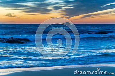 Sunrise at the beach with high cloud and boat with lights Stock Photo