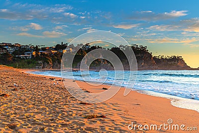 Sunrise at the Beach with light cloud and headland with houses Stock Photo