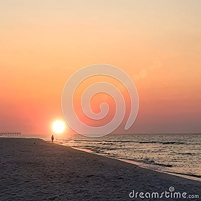 Sunrise at the Beach with One Person Walking Along the Shoreline. Stock Photo