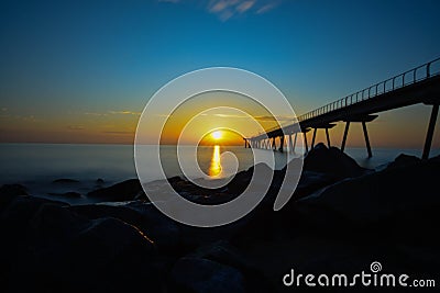 Sunrise over the beach with the pont del petroli and the rocks as a company Stock Photo