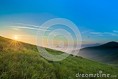 Sunrise over hills in mountains with green grass and blue sky wi Stock Photo