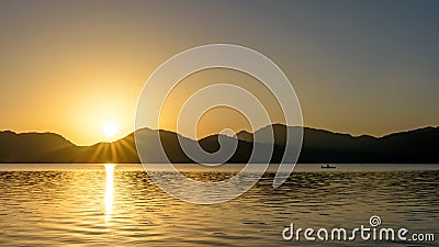 Sunrise over mountains and lake with canoeist Stock Photo